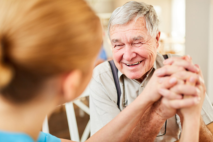 caregiver holding hands with a smiling senior