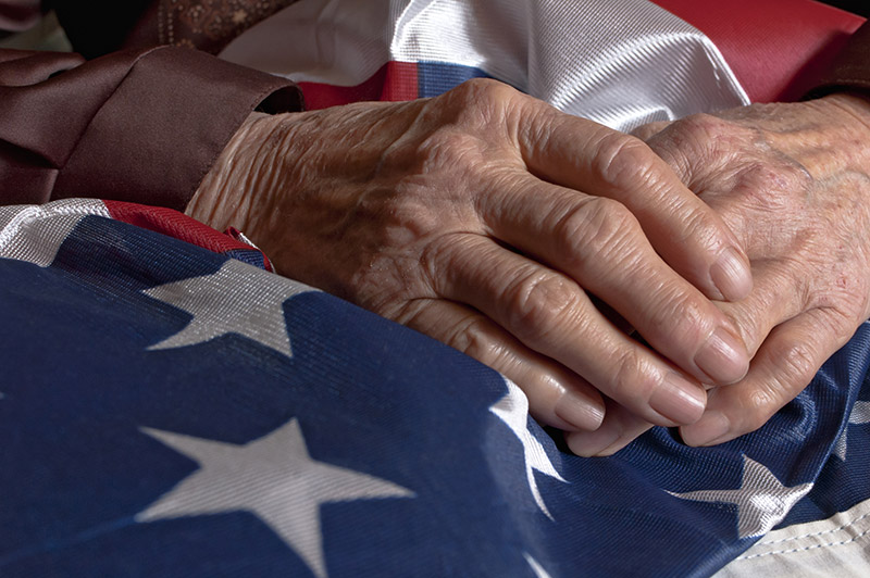 Veterans hands on top of a flag